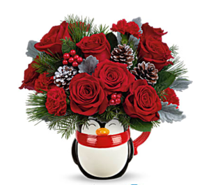Bouquet of red roses, carnations, dusty miller, douglas fir and white pine in a "send a hug" penguin mug.